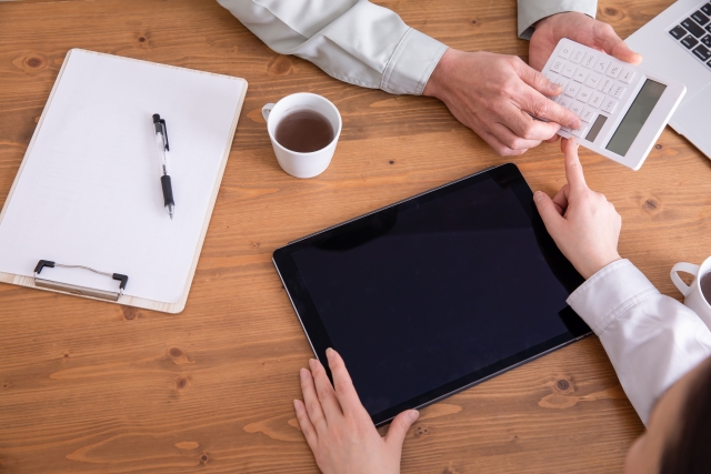 タブレットと電卓を触っている手