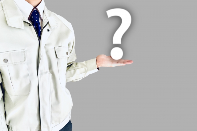 作業服を着た男性の手に？が乗っている写真